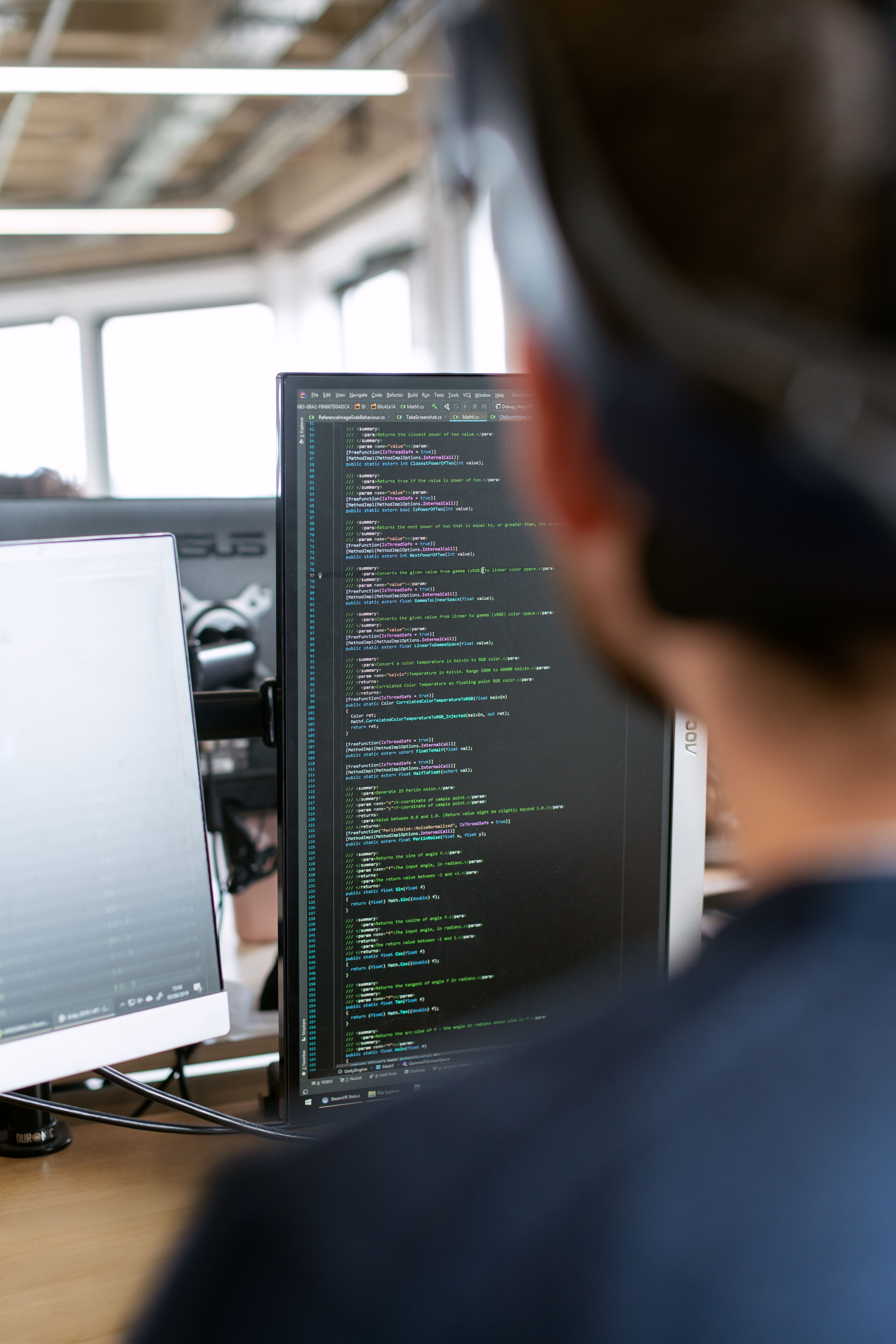 Developer working at a vertical coding monitor in a bright studio.